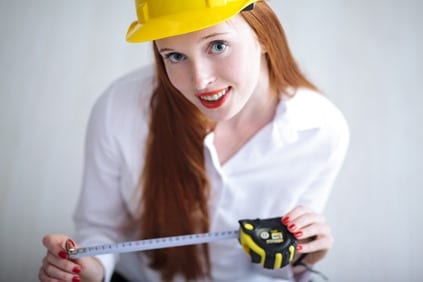 Young beautiful female with yellow helmet holding a tape measure